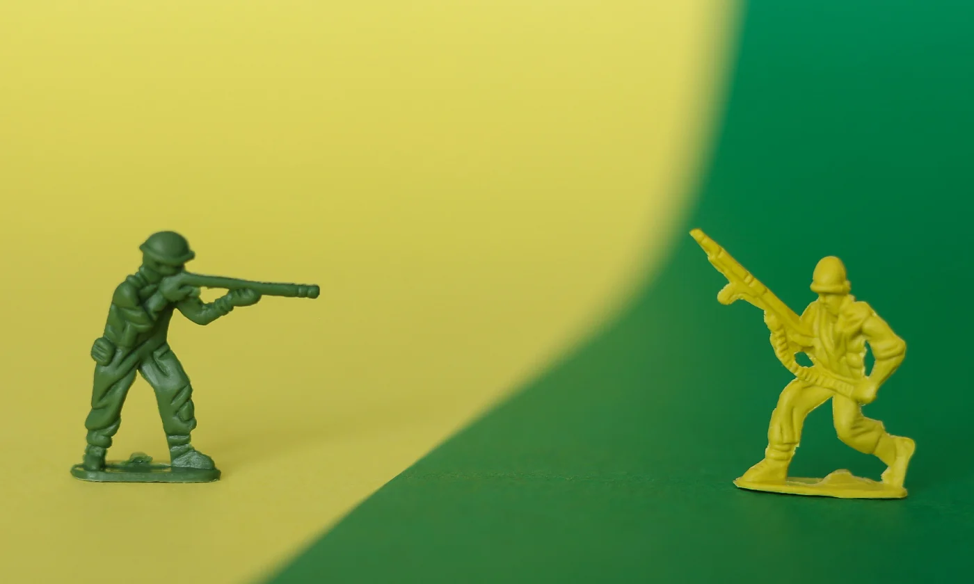 A macro photo of two plastic toy soldiers facing each other.