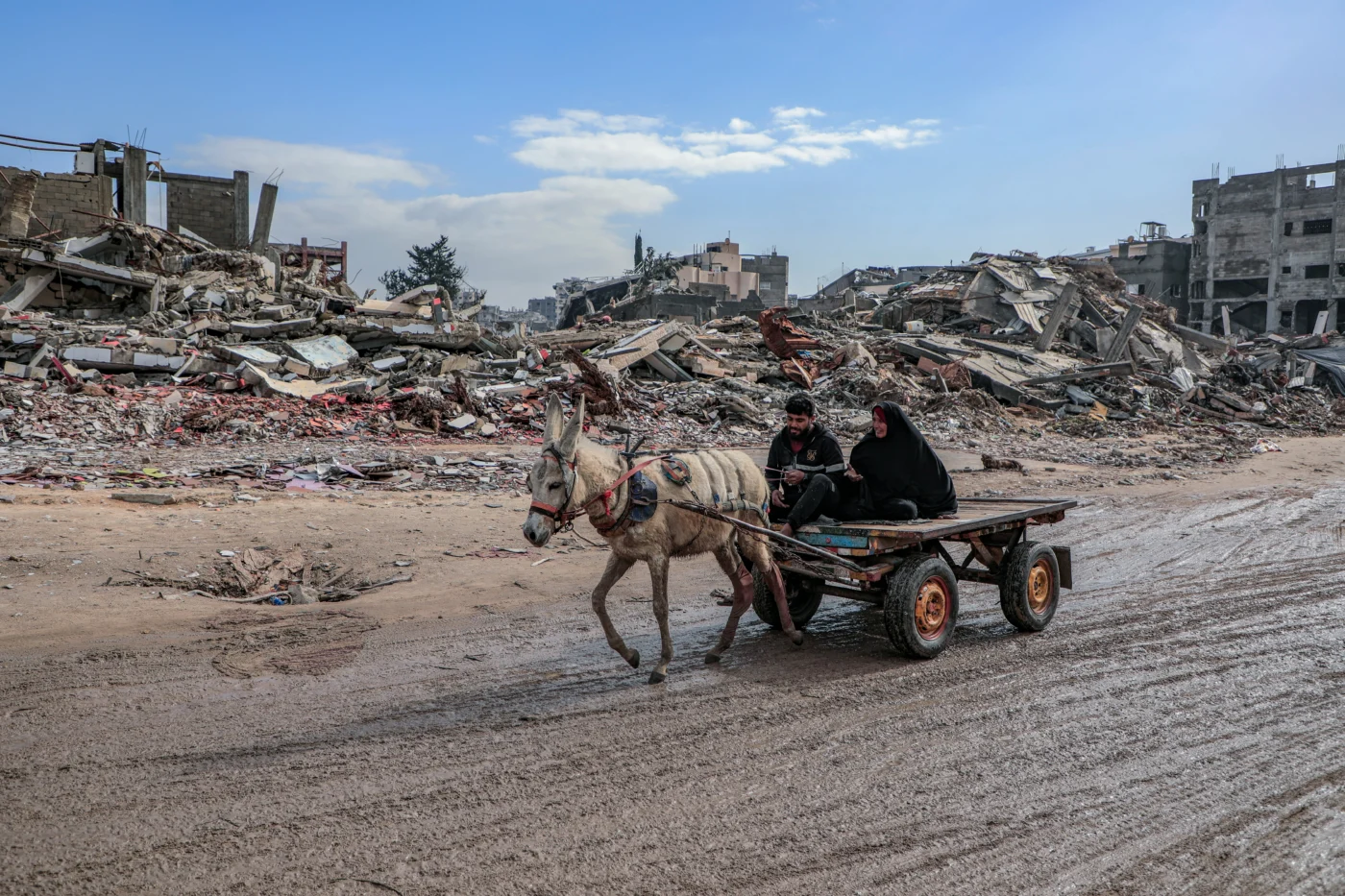 Amid the massive destruction in Jabalia camp, Gaza-Palestine, a young man and his mother drive a cart through the camp's streets