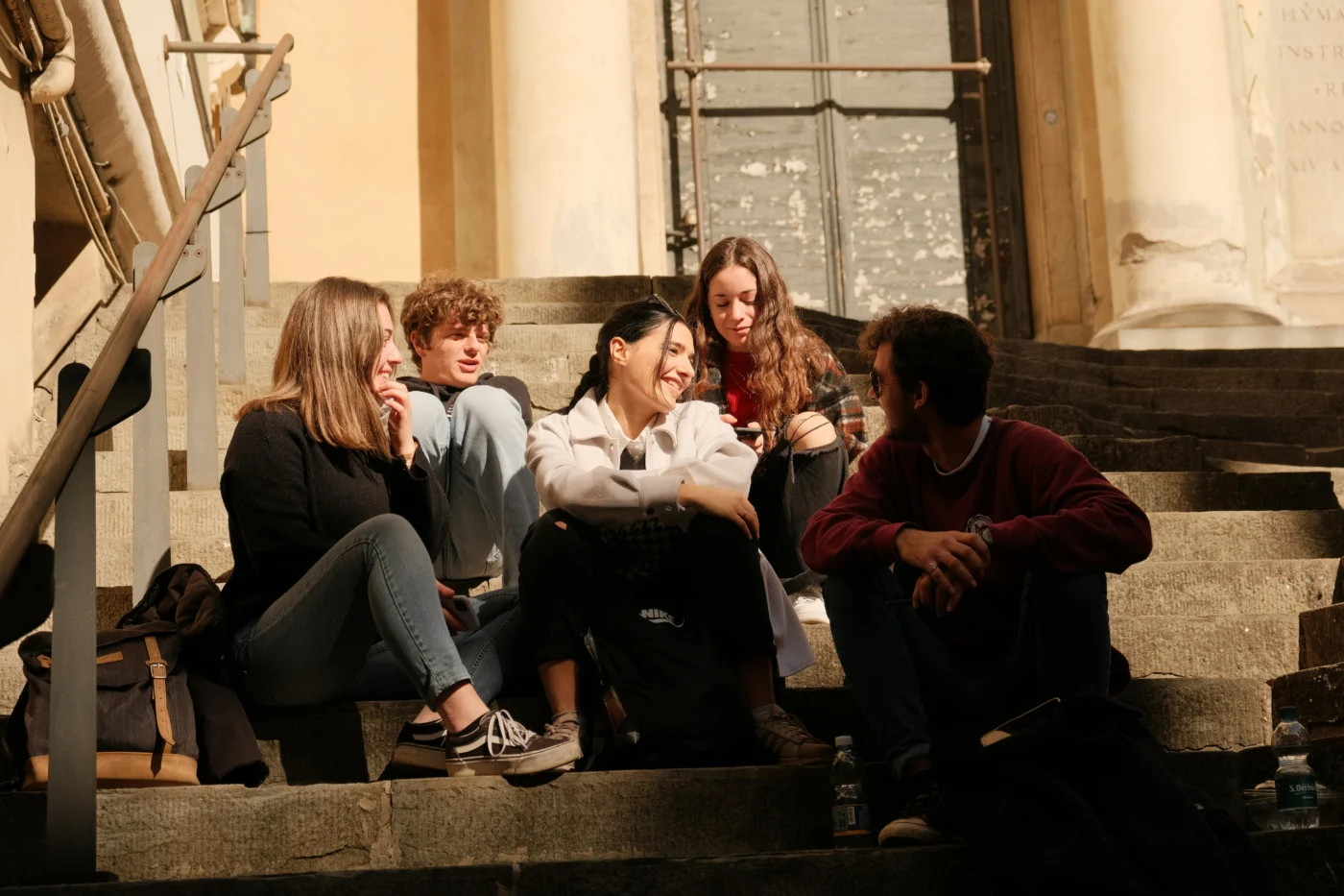 A group of young people sitting on the steps of a building.
