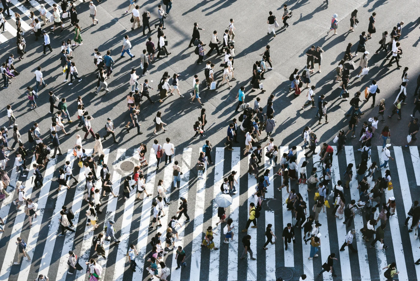 Aerial view of dozens of pedestrians walking across Shibuya Crossing in Tokyo, Japan.