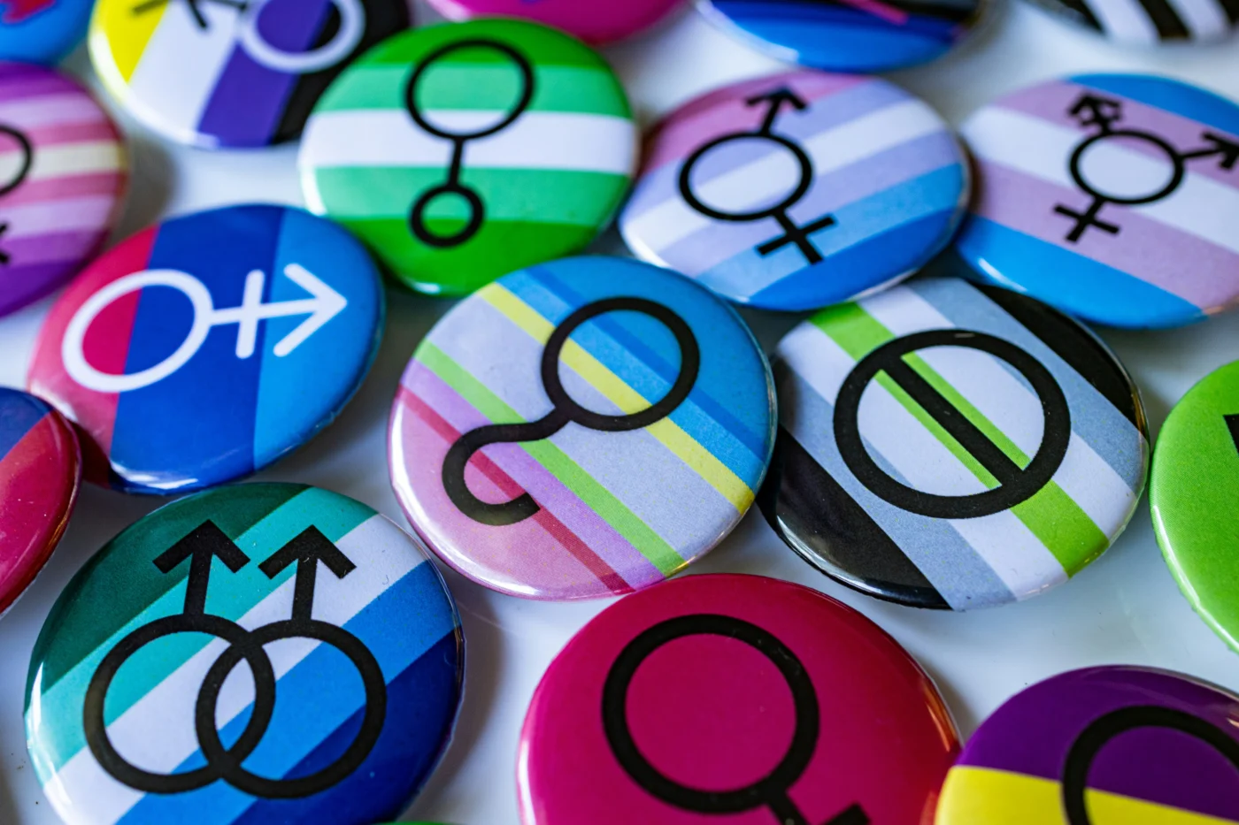 A pile of colourful pin badges featuring various gender identity symbols.