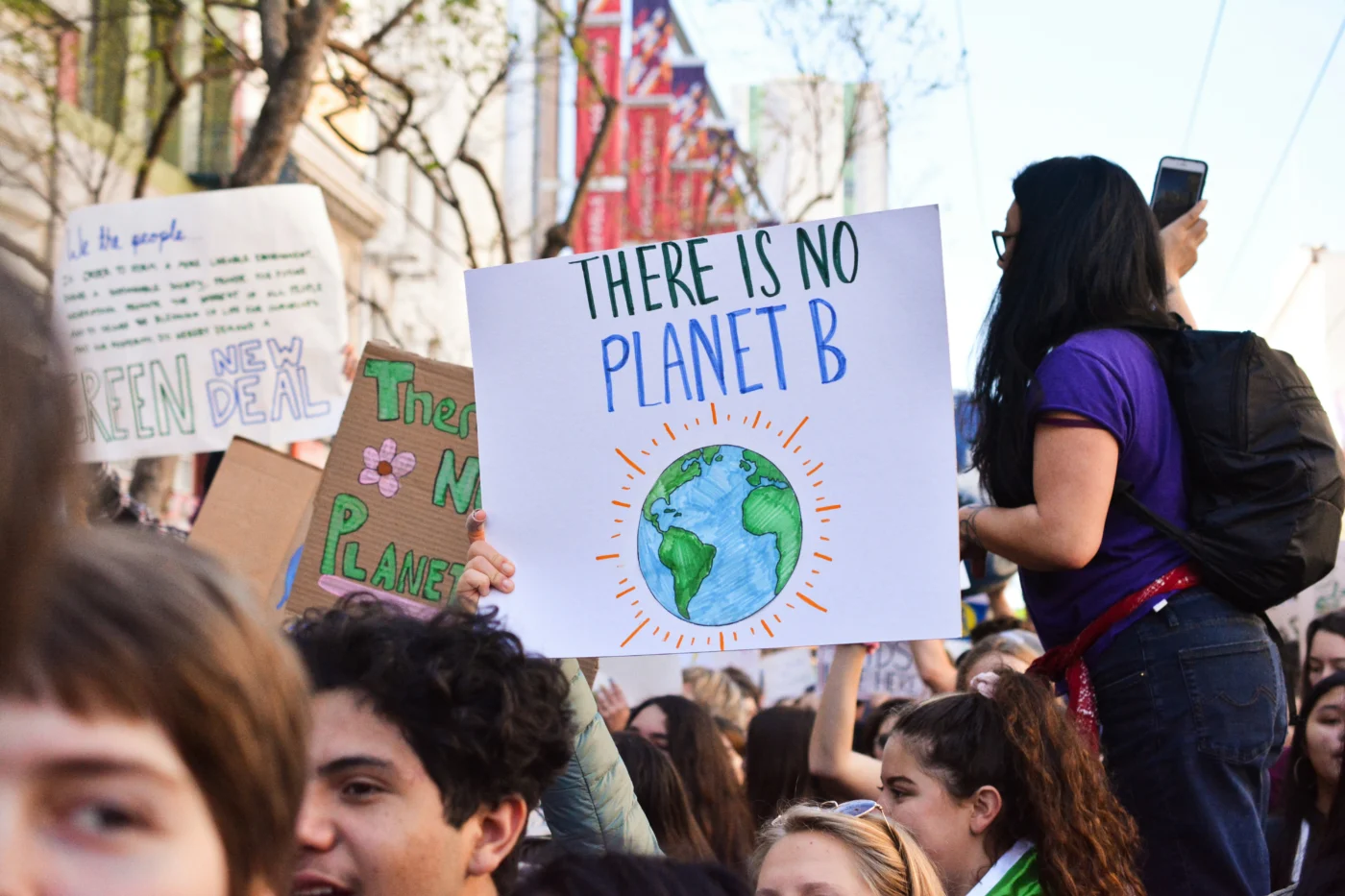 Protestors holding placards at a climate protest in Union Square, San Francisco, United States. A sign with an illustration of planet Earth reads "THERE IS NO PLANET B".