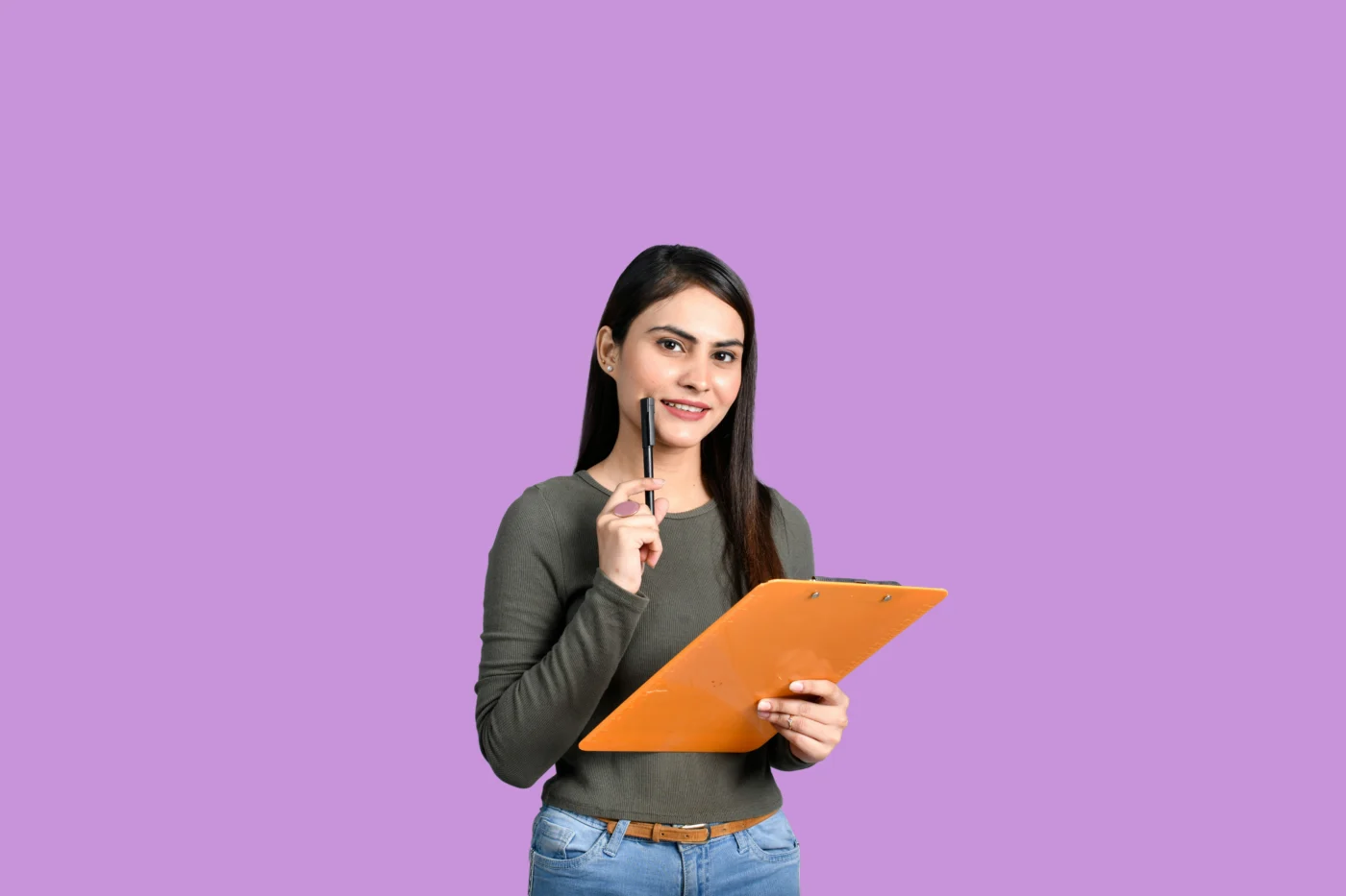 A woman standing in front of a bright pink background and holding a pen and clipboard.