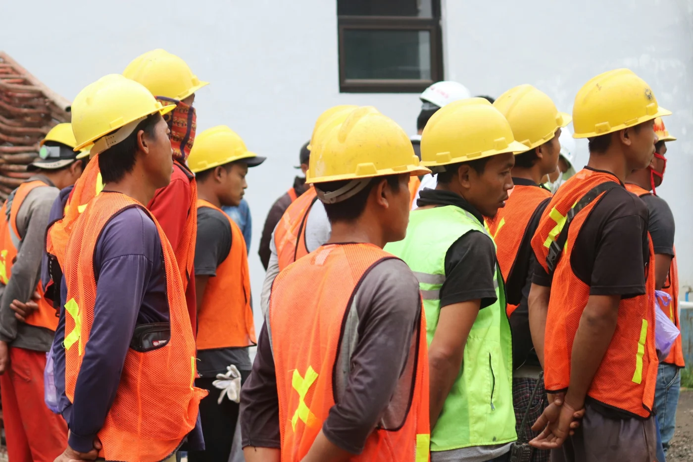 A group of construction workers wearing high-visibility workwear and hard hats in Indonesia.